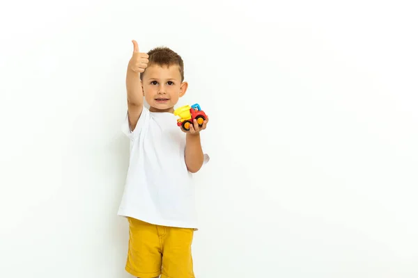 Portrait d'un petit garçon riant avec les pouces vers le haut signe sur fond gris — Photo