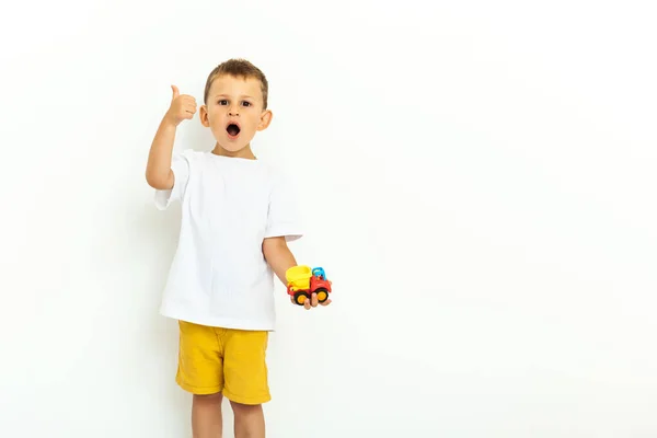 Porträtt av en liten pojke som skrattar med tummen upp tecken på grå bakgrund — Stockfoto