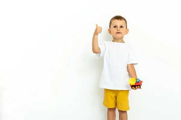 Retrato de un niño riéndose con el pulgar hacia arriba sobre fondo gris —  Fotos de Stock