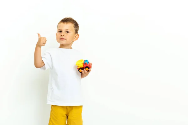Porträtt av en liten pojke som skrattar med tummen upp tecken på grå bakgrund — Stockfoto