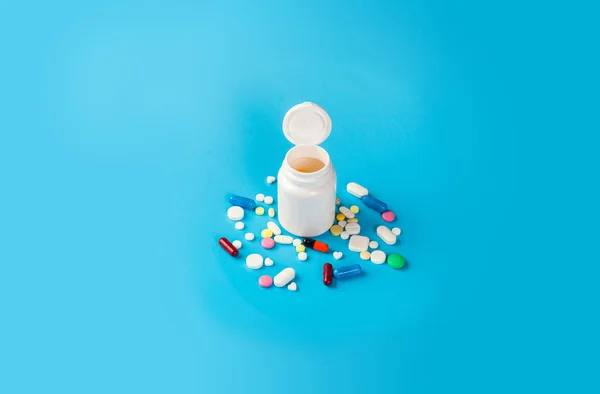 Pastillas, tabletas y cápsulas medicinales sobre fondo azul — Foto de Stock
