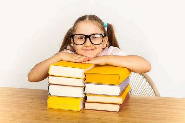 Sorridente piccola studentessa con molti libri a scuola — Foto Stock