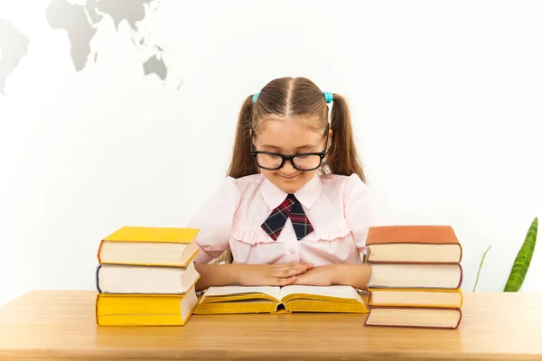 Sorridente piccola studentessa con molti libri a scuola — Foto Stock