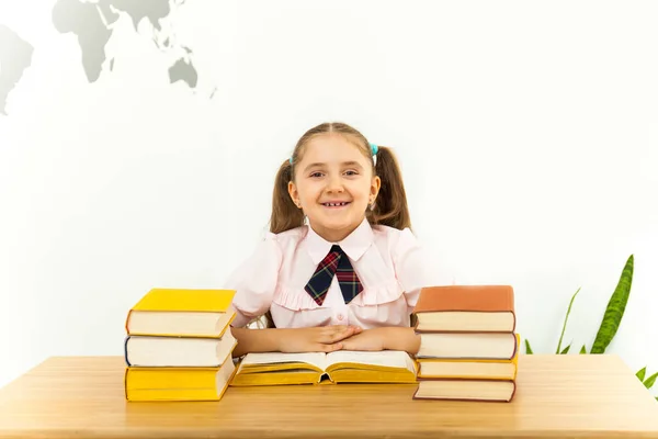 Sorridente piccola studentessa con molti libri a scuola — Foto Stock