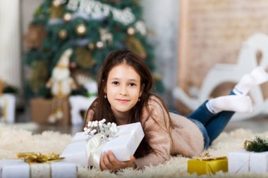 Noel ağacının önündeki hediye kutularıyla çocuk kız..