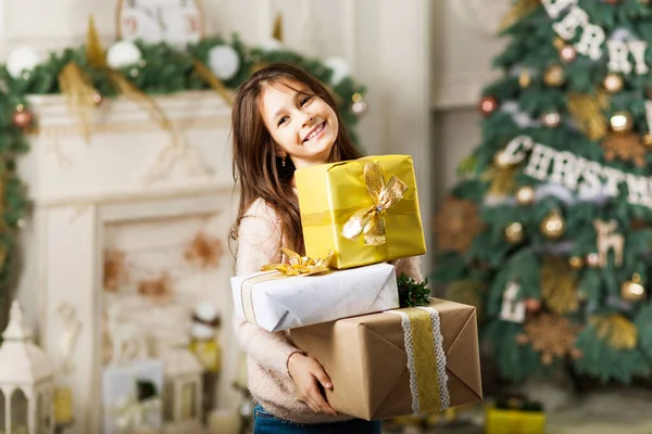 Dítě dívka v přední vánoční strom s dárkové krabice. — Stock fotografie