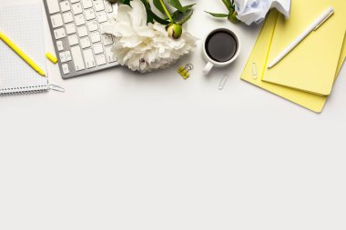 Boş defter, klavye, ofis malzemeleri, sarı ve beyaz kalemler, buruşmuş kağıt top ve beyaz arka planda kahve fincanı olan ofis masası..