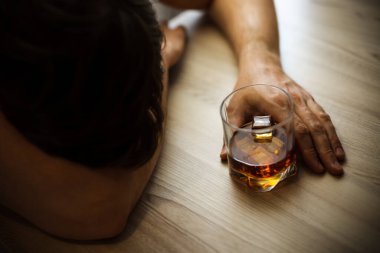 Bunalımlı bir adam, sarhoş, elinde bir bardak viski, yoksulluk, alkolizm ve depresyon konseptiyle masada uyuyor. Yumuşak odak