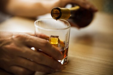 Eller bardağa içki doldurur. Alkolizm sorunu. Alkolün kötüye kullanımı. Sosyal ve ailevi sorunlar. Yumuşak odak