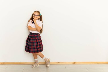 İki kuyruklu, resmi bluzlu, beyaz arka planda kırmızı etekli, tam vücut ölçülerinde bir kız.