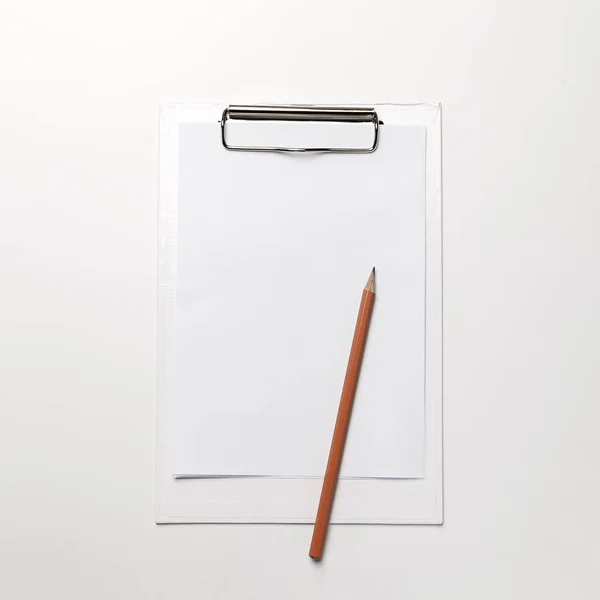 白いテーブルの上に紙と鉛筆の空白のシートと白いクリップボード トップビューオフィスアクセサリーコンセプト — ストック写真