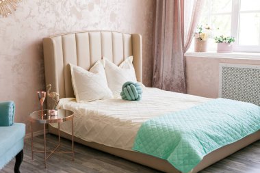 Pembe, mavi ve altın renkli, büyük pencereli, klasik kapılı, bej renkli yataklı, altın aynalı kahve masalı parlak yatak odasının gerçek fotoğrafı.