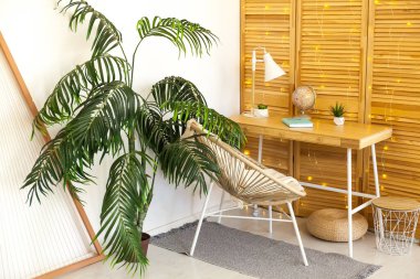 Masası, sandalyesi, oturma odasında beyaz lambası olan rahat bir iş yeri.