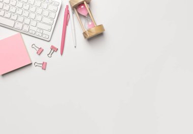 Klavyeli ofis masası, çıkartma notu, kalem, pembe kum saati. Kopyalama alanı olan üst görünüm