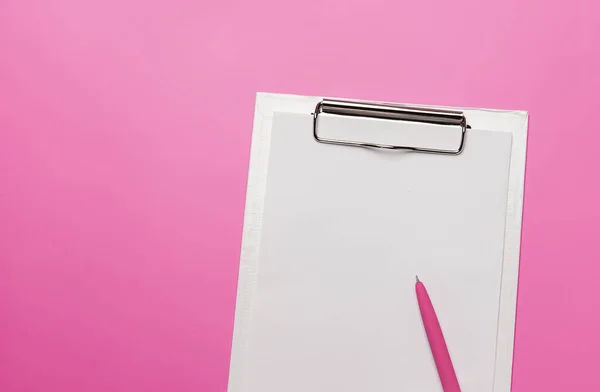 白色的剪贴板 空白的纸和笔粉红色的背景 顶级写字楼配件概念 — 图库照片