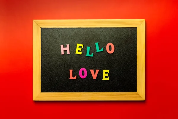 Hello Love word made with wooden letters on the Blackboard surface composition on Red background. Love concept