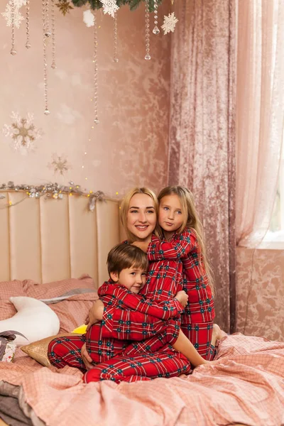 Szczęśliwe Dzieci Przytulają Mamę Uśmiechają Się Szczęśliwa Rodzina Czerwonej Piżamie — Zdjęcie stockowe