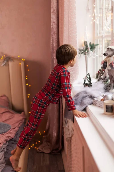 Netter Neugieriger Junge Karierten Pyjama Der Durch Ein Fenster Blickt — Stockfoto