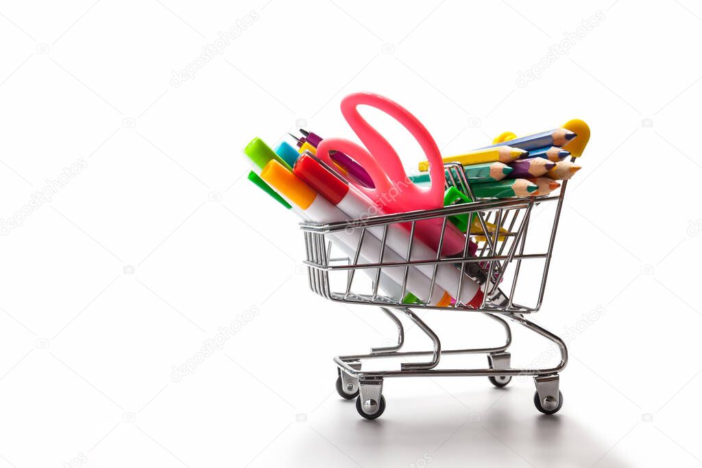 Shopping trolley filled with multicolored school supplies on a white background. Back to school concept