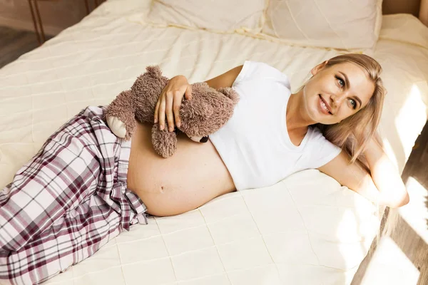 人与期望概念 怀孕妇女在家中与泰迪熊同床休息 — 图库照片