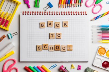 Okul ofis malzemeleri ve bir masanın üzerinde ahşap bloklardan yapılmış okul metinleri olan bir defter.