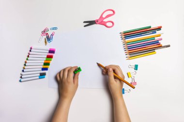 Küçük el çizimleri, boş kağıtlar ve eski beyaz masa üzerindeki renkli kalemler.