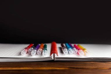 Siyah arkaplan ile açılan dizüstü bilgisayarda çok renkli akrilik işaretleyiciler