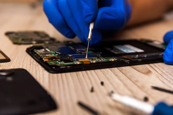 The technician repairing the smartphone\'s motherboard in the workshop on the table. Concept of computer hardware, mobile phone, electronic, repairing, upgrade and technology.