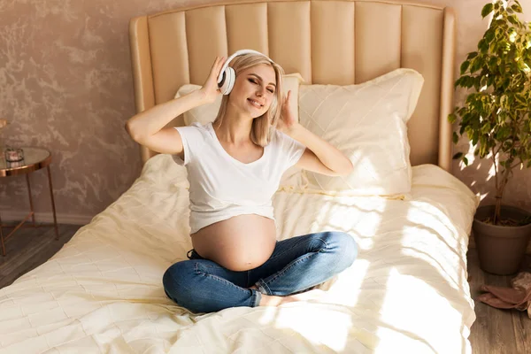 Mooie Zwangere Vrouw Zitten Bed Lotus Positie Thuis Luisteren Muziek — Stockfoto