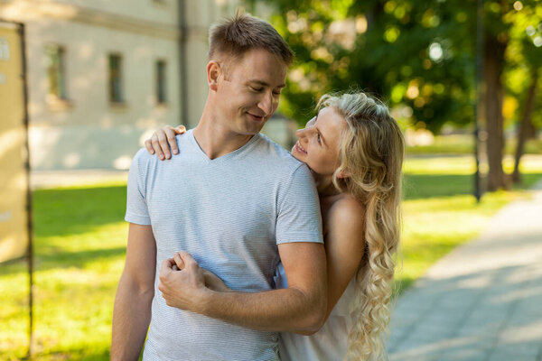 Счастливы быть вместе. Портрет красивой молодой любящей пары, улыбающейся, глядя друг на друга, стоя на улице