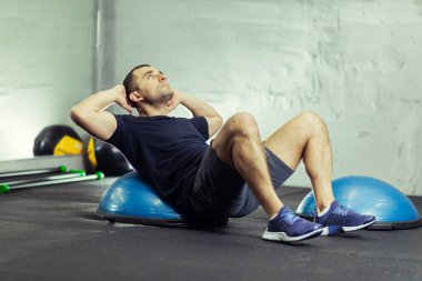Yakışıklı bir adamın portresi fitness topunda basını sallıyor.