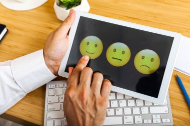 Tablette, tahta masada, koyu arkaplanda renkli ifadelerin temsili ile olumlu değerlendirme. Yatay bileşim. Üst görünüm.