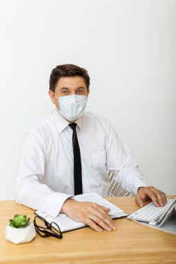 Viral tehdit, mevsimsel viral hastalıklar. Ofiste tıbbi maskeli bir adam çalışıyor, ofis çalışanlarını virüslerden koruyor.