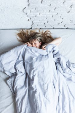 Güzel gülümseyen genç sarışın kadın battaniyenin altında