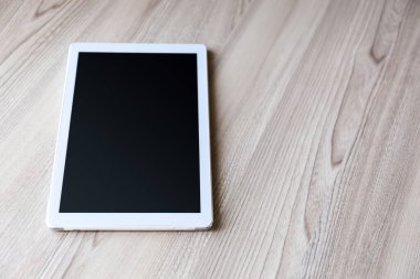 Eski ahşap arka planda ipad mini gibi görünen beyaz tablet.