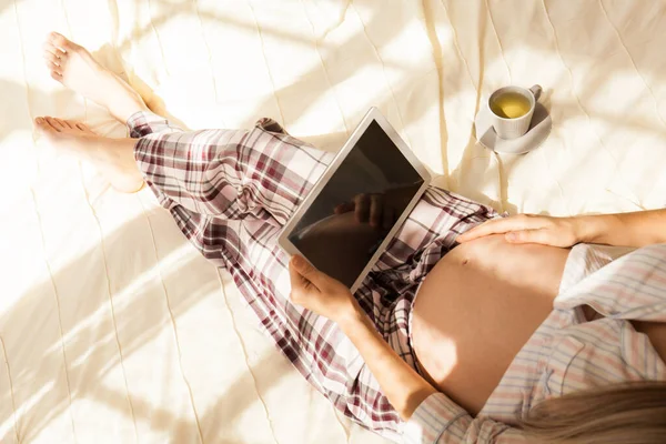 침대에 누워서 타블렛을 임산부의 사진입니다 임신중 온라인 쇼핑과 기술의 — 스톡 사진