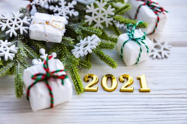 Ahşap bir arka planda 2021 numaralı Noel süslemeleri, ladin yeşil dalları, hediyeler ve kar taneleri. Yeni yıl konsepti