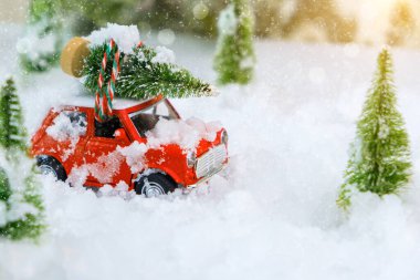 Kırmızı antika bir oyuncak, karlı kış harikalar diyarında bir Noel ağacını eve taşıyor. Araç üzerinde seçici odaklı aşırı sığ alan derinliği