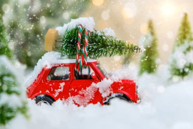 Kırmızı antika bir oyuncak, karlı kış harikalar diyarında bir Noel ağacını eve taşıyor. Araç üzerinde seçici odaklı aşırı sığ alan derinliği