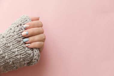 Kadın el manikürü. Pembe arka planda örülü süveter. Moda Geometrik Tırnak Sanatı Manikürü. Manikür salonu afişi
