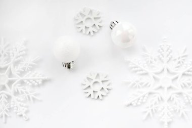 Beyaz toplardan ve beyaz arka planda kar tanelerinden oluşan Noel deseni. Noel, kış, yeni yıl konsepti. Düz konum, üst görünüm, kopyalama alanı
