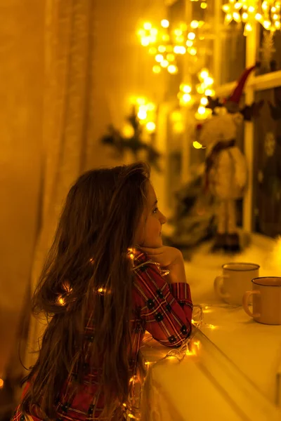 明るいガーランドと古典的な暗い背景と暖かい光を持つ缶と魔法の神秘的な女の子の子供 クリスマスの期待と居心地の良い暖かいスタイル — ストック写真