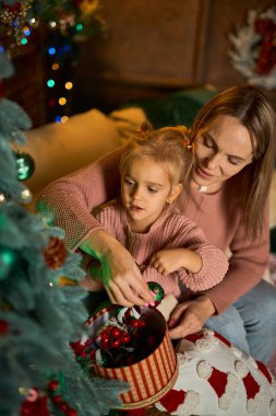 Kadın ve çocuk, Noel ağacını hediyeler, çelenkler, sıcak ışıklar, şenlik havası ve aile bağlarıyla donatır.