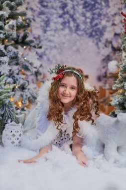 Güzel bir Noel stüdyosunda, yumuşak, sahte kar altında duran neşeli saç bandıyla güzel bir kız poz veriyor. Arkaplanda pırıl pırıl ışıklar ve kar kaplı ağaçlar, tatil temalı projeler konsepti yer alıyor.