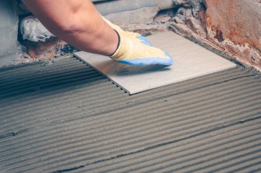 Çini karo yere çentikli bir mala tarafından uygulanan bir yapıştırıcı ile ahşaba yapıştıran bir ürüne