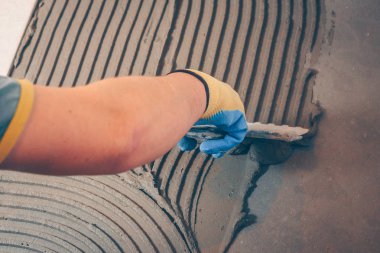 Tiler fayans montajı için yere tutkal uygular