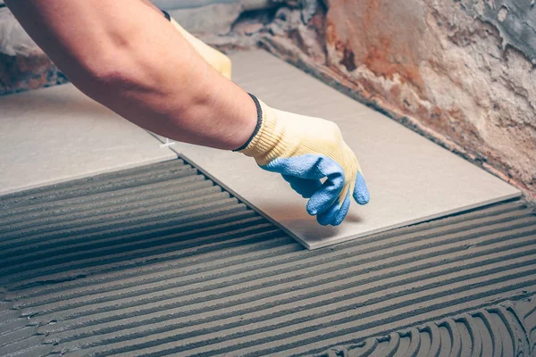 Kiris yerde sarı eldiven kare fayans ellerini koyar