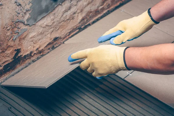 İşçi kare karoyu dikkatlice yere koyar.