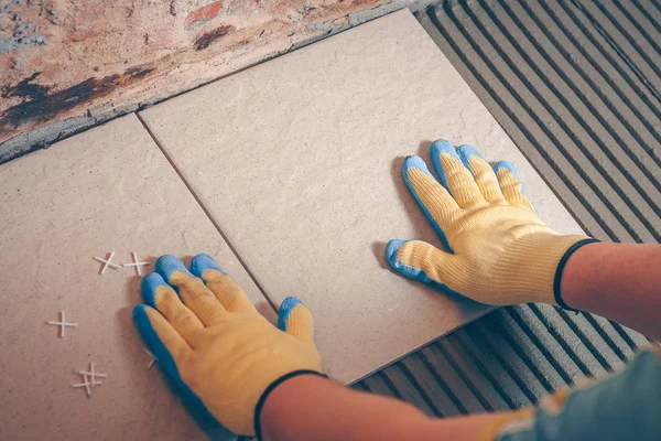 Kiris yerde sarı eldiven kare fayans ellerini koyar