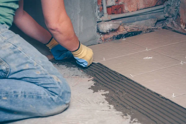 Kiris yerde sarı eldiven kare fayans ellerini koyar